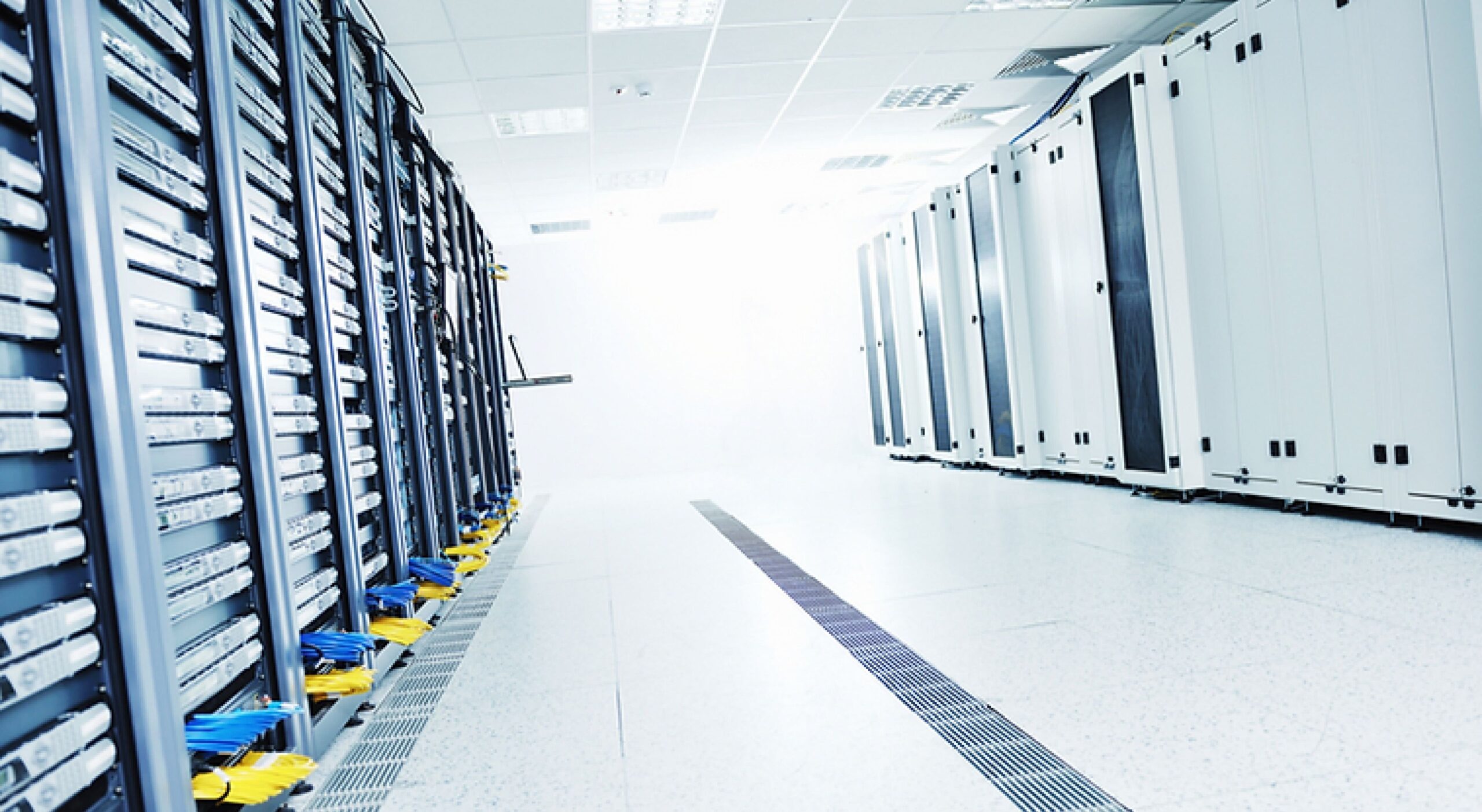 Brightly lit data center hallway lined with server racks (white space)
