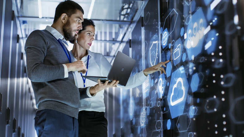IT professional in a data center monitoring servers on wall-mounted screens