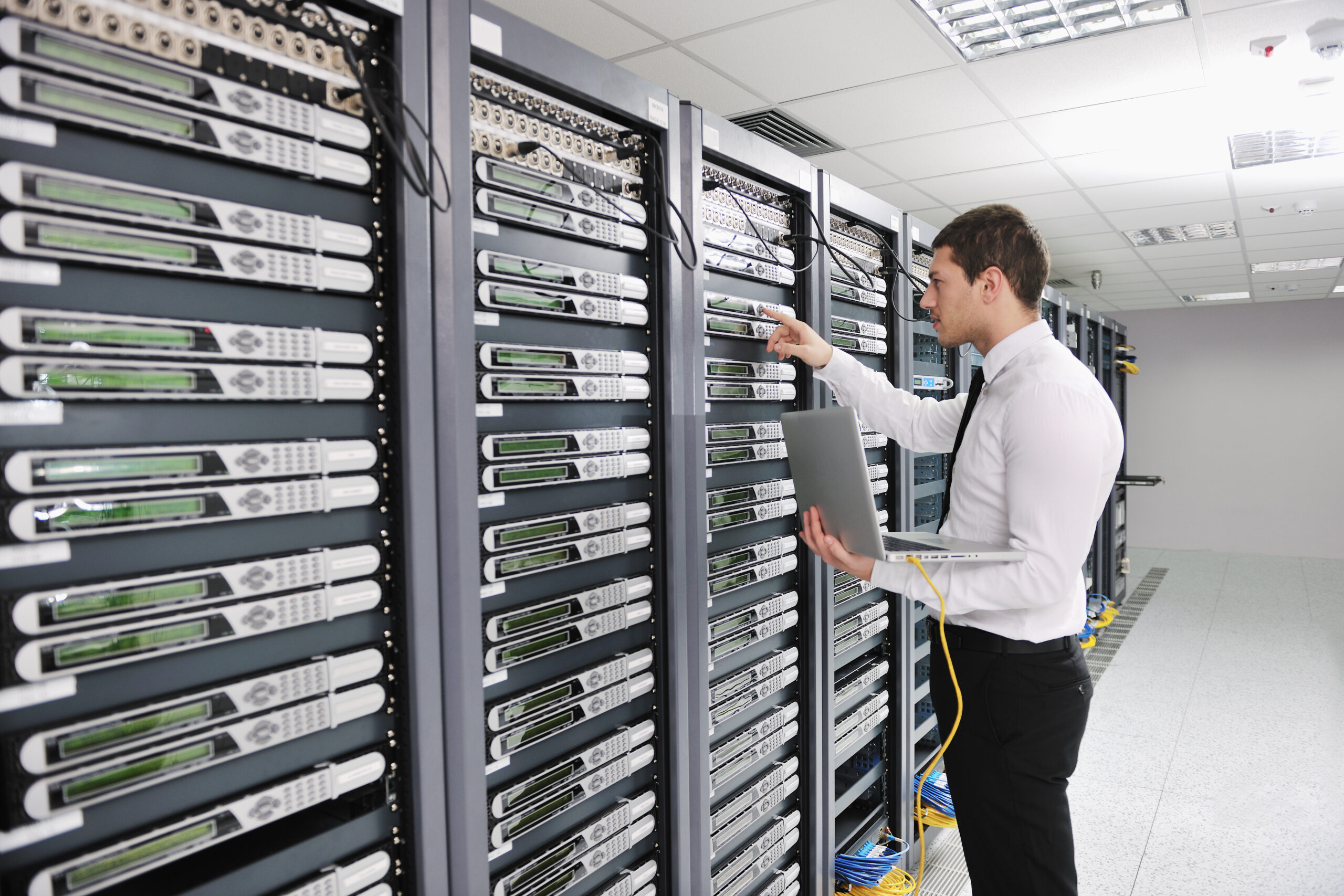 A business professional standing in a data center aisle between server racks