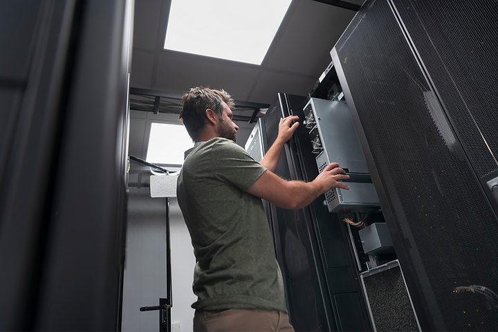 An IT professional pulling a server unit out of a data center rack